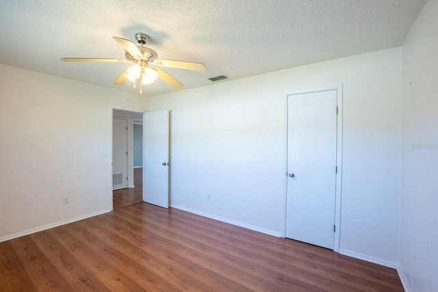 unfurnished bedroom with visible vents, a textured ceiling, and wood finished floors