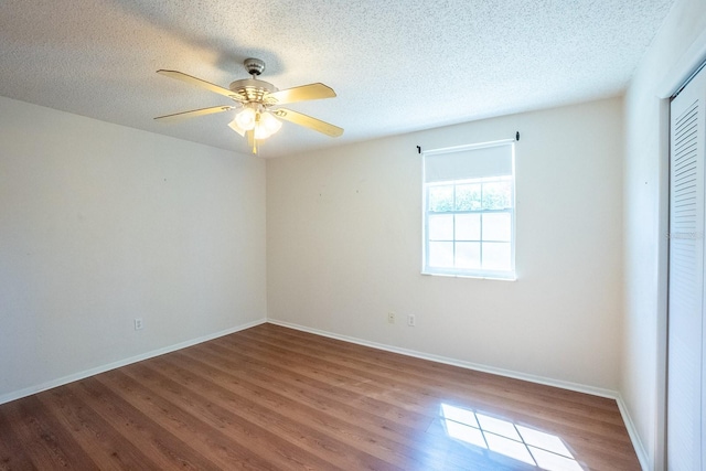 spare room featuring baseboards, a textured ceiling, wood finished floors, and a ceiling fan