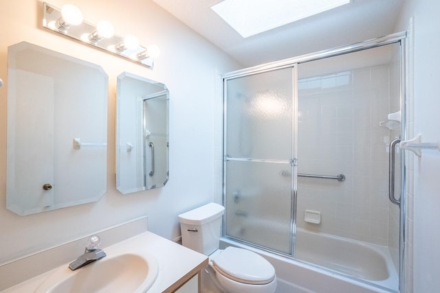 full bathroom with bath / shower combo with glass door, a skylight, vanity, and toilet