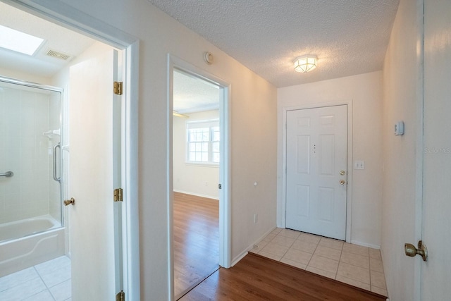 interior space with baseboards, wood finished floors, visible vents, and a textured ceiling