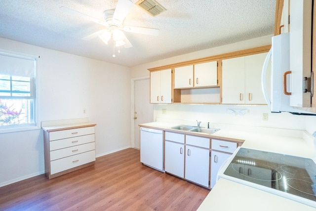 kitchen featuring visible vents, a sink, a textured ceiling, white appliances, and light wood-style floors