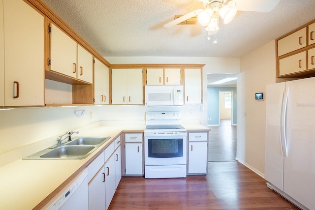 kitchen featuring white appliances, dark wood finished floors, a sink, light countertops, and a textured ceiling