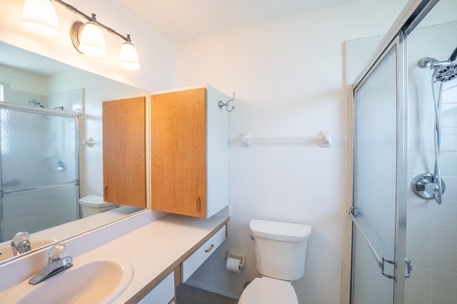 full bath with vanity, a shower stall, and toilet