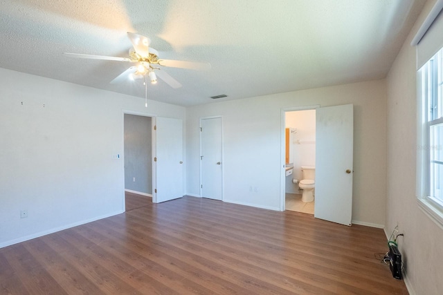 empty room with visible vents, a textured ceiling, a ceiling fan, and wood finished floors