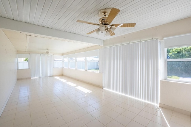 unfurnished room with beamed ceiling, a ceiling fan, and tile patterned flooring