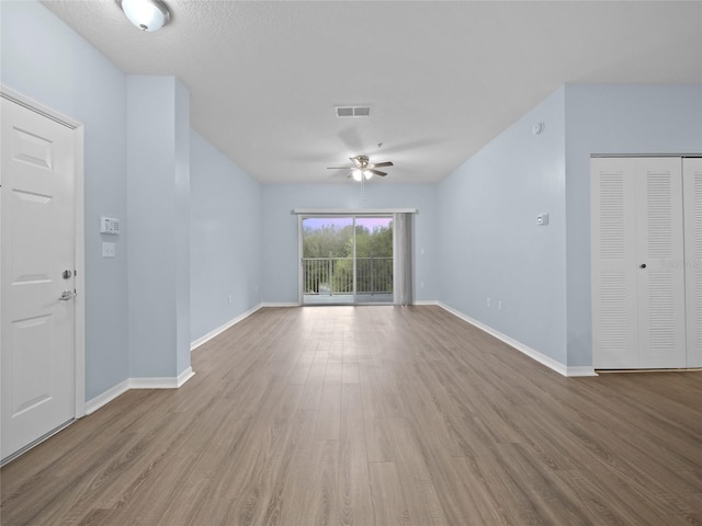 unfurnished living room featuring a ceiling fan, baseboards, and wood finished floors