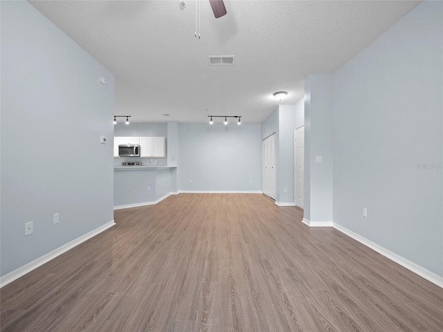 unfurnished living room featuring visible vents, ceiling fan, a textured ceiling, wood finished floors, and baseboards