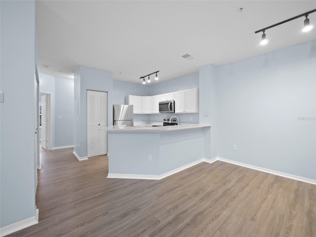 kitchen featuring visible vents, wood finished floors, a peninsula, stainless steel appliances, and white cabinetry