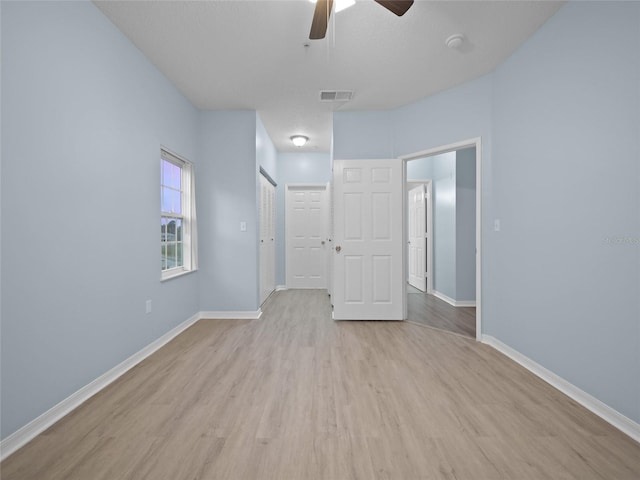 interior space with light wood-style floors, baseboards, visible vents, and a ceiling fan