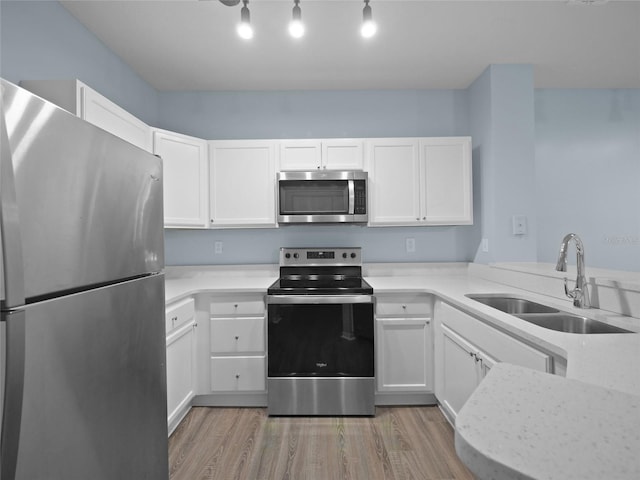 kitchen featuring stainless steel appliances, light wood-type flooring, light countertops, and a sink