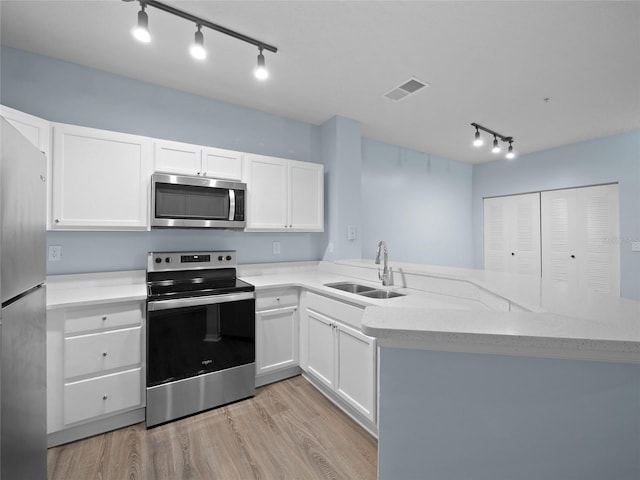 kitchen with white cabinets, light stone counters, appliances with stainless steel finishes, light wood-style floors, and a sink