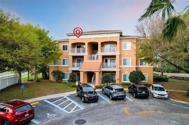 view of building exterior featuring uncovered parking and fence