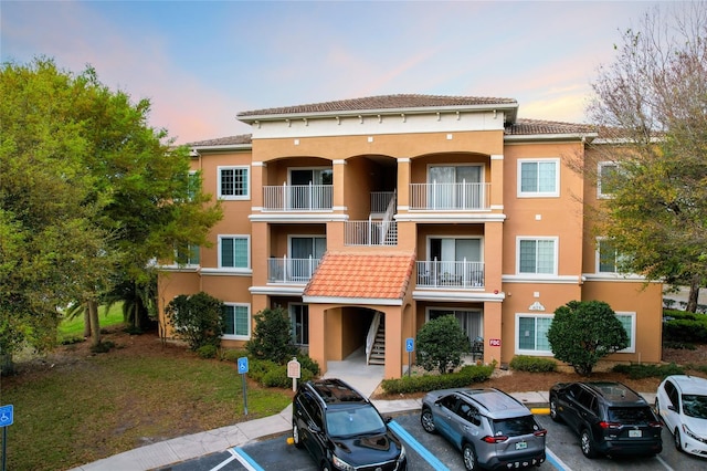 property at dusk featuring uncovered parking and stairway