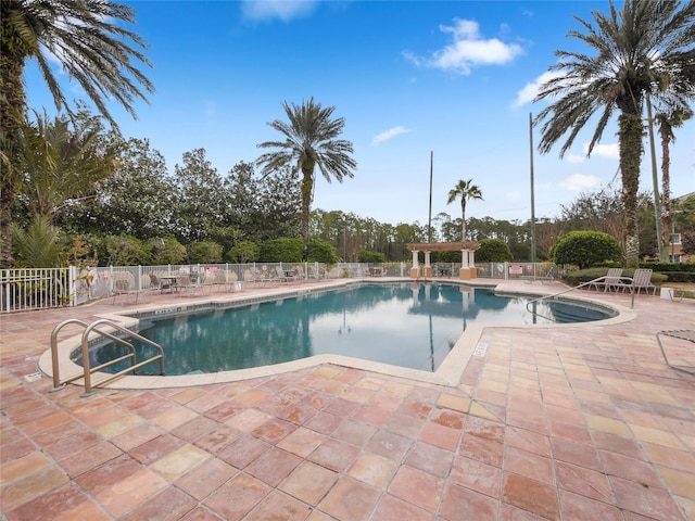 pool with a patio area and fence