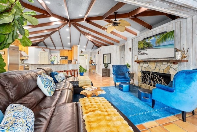 tiled living area with a ceiling fan, vaulted ceiling with beams, a fireplace, and wooden walls