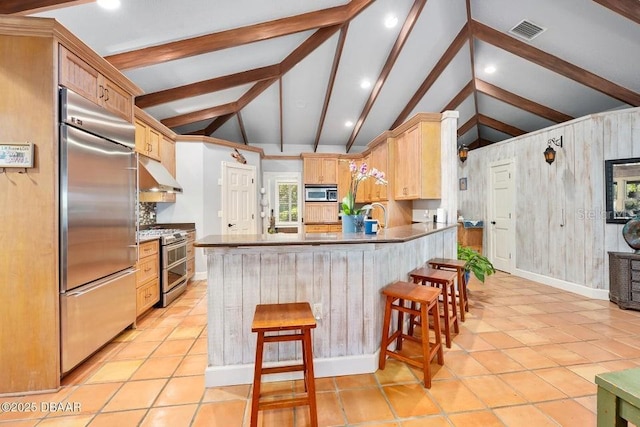 kitchen featuring vaulted ceiling with beams, stainless steel appliances, visible vents, a peninsula, and under cabinet range hood