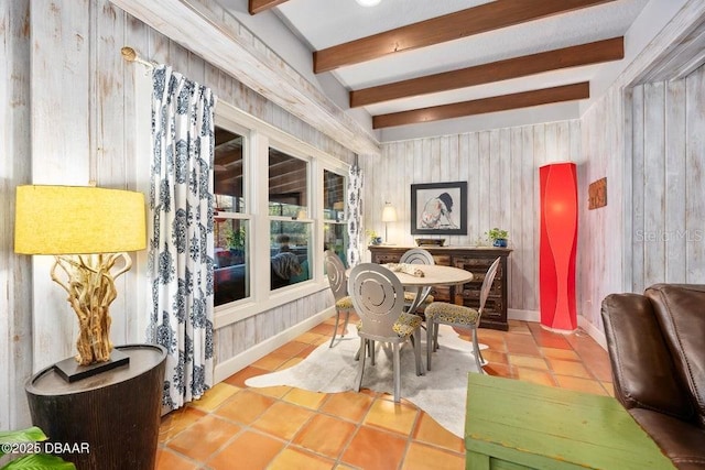 tiled dining room featuring beam ceiling