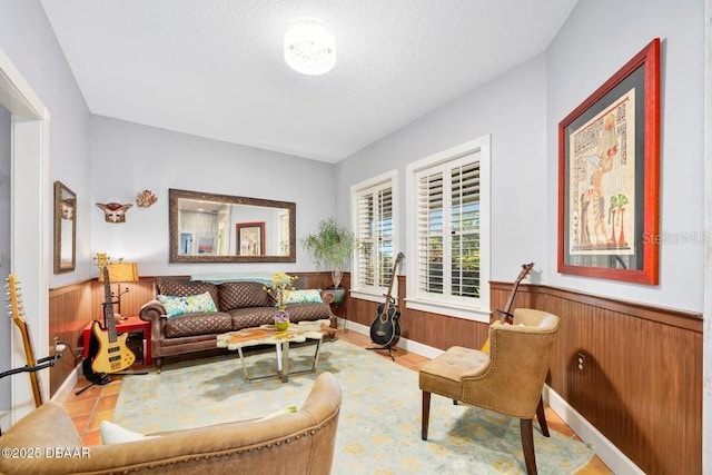 living area featuring wainscoting, wood walls, and a textured ceiling