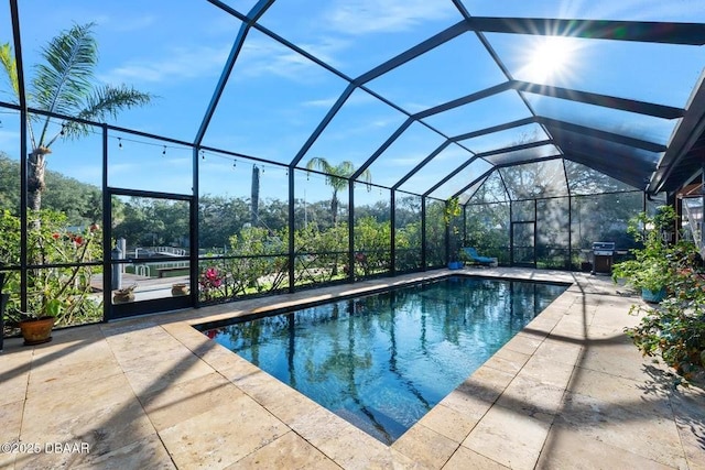 outdoor pool with a patio area, glass enclosure, and area for grilling