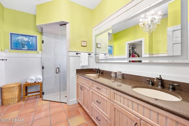 full bathroom with a stall shower, tile patterned flooring, wainscoting, and a sink