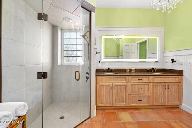 full bath featuring double vanity, a stall shower, tile patterned flooring, and a sink