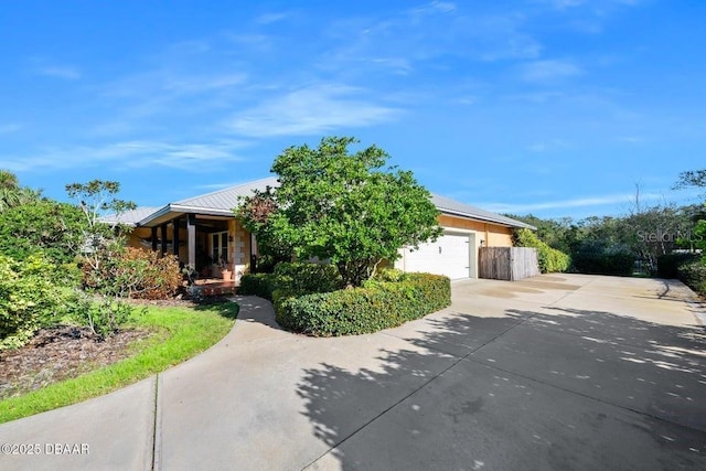 obstructed view of property with a garage, metal roof, and concrete driveway