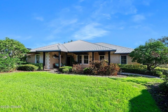 rear view of property with a lawn, stone siding, metal roof, a standing seam roof, and stucco siding