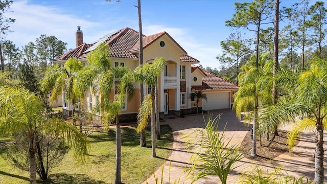 mediterranean / spanish-style house with a tile roof, stucco siding, a garage, driveway, and a front lawn