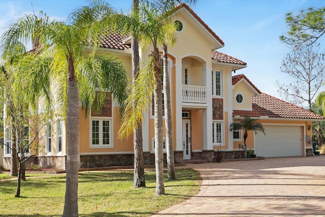 mediterranean / spanish home with a garage, a balcony, a tile roof, and stucco siding