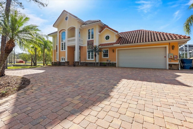 mediterranean / spanish home featuring a garage, a tiled roof, decorative driveway, and stucco siding