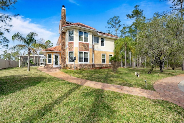 back of house featuring a chimney, stucco siding, a lawn, a lanai, and stone siding