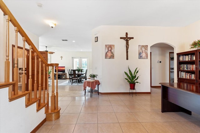 hallway featuring stairs, light tile patterned floors, arched walkways, and visible vents