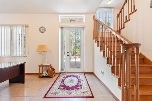 entrance foyer featuring stairs, light tile patterned flooring, and baseboards