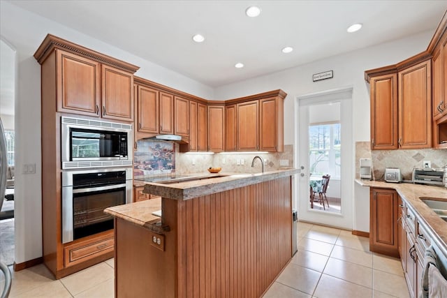 kitchen featuring light tile patterned floors, appliances with stainless steel finishes, a kitchen island, and tasteful backsplash