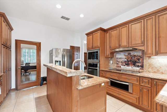 kitchen with a center island with sink, appliances with stainless steel finishes, light tile patterned flooring, a sink, and a warming drawer