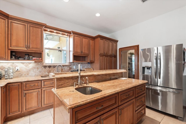 kitchen with a sink, stainless steel refrigerator with ice dispenser, open shelves, tasteful backsplash, and brown cabinetry