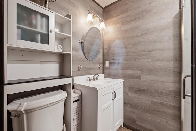 bathroom featuring wooden walls, vanity, and toilet