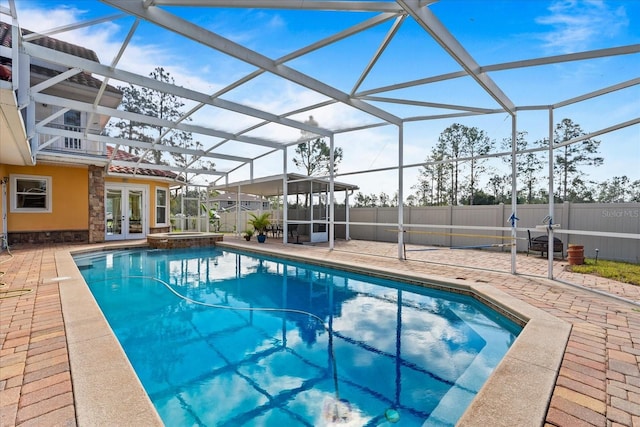 view of pool with a patio, glass enclosure, fence, a pool with connected hot tub, and french doors