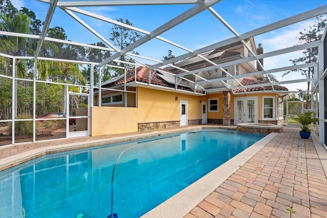 view of pool featuring a lanai, a patio area, a pool with connected hot tub, and french doors