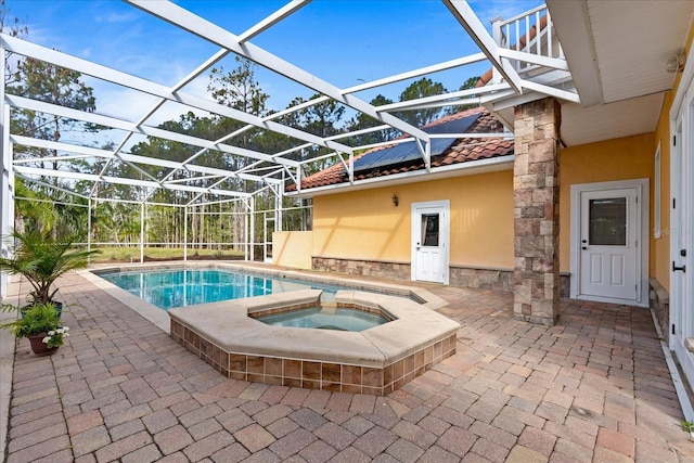 outdoor pool with glass enclosure, a patio, and an in ground hot tub