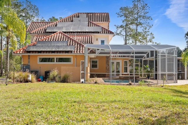 rear view of property featuring glass enclosure, french doors, a lawn, an outdoor pool, and stucco siding