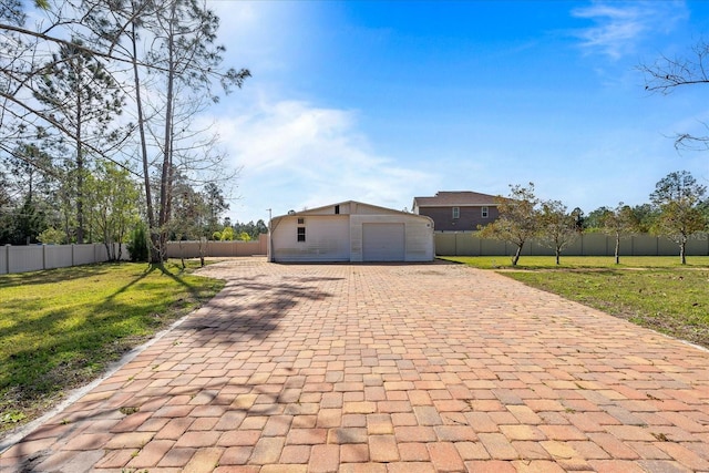 exterior space featuring a garage, fence private yard, an outdoor structure, and a front lawn