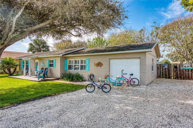 back of property with a garage, gravel driveway, fence, a yard, and a patio area