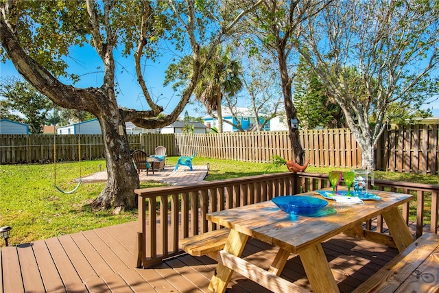 wooden terrace featuring a fenced backyard, outdoor dining area, a lawn, and a patio