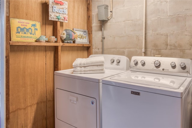 laundry room featuring concrete block wall, laundry area, and washing machine and clothes dryer