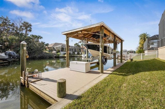 dock area with a lawn, a water view, boat lift, and fence