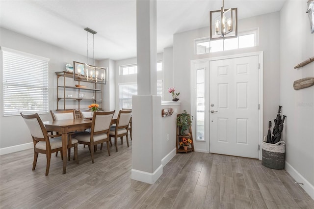 entryway featuring light wood finished floors, a wealth of natural light, and an inviting chandelier