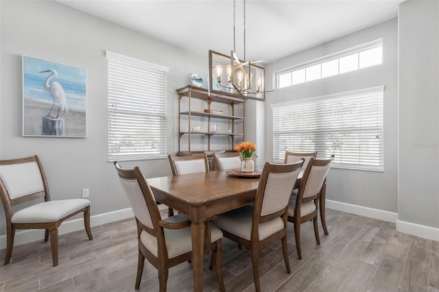 dining area with baseboards, light wood finished floors, and an inviting chandelier