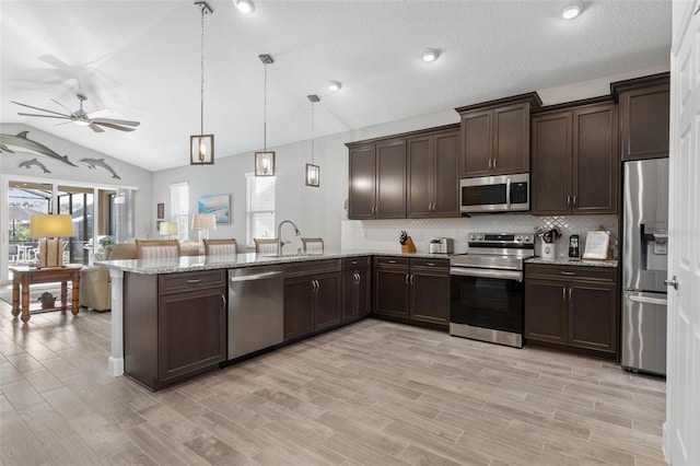 kitchen with tasteful backsplash, lofted ceiling, appliances with stainless steel finishes, dark brown cabinets, and a peninsula