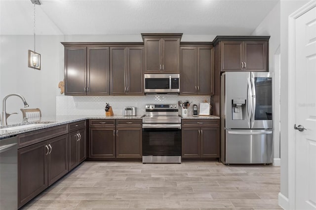 kitchen featuring backsplash, dark brown cabinets, stainless steel appliances, and a sink